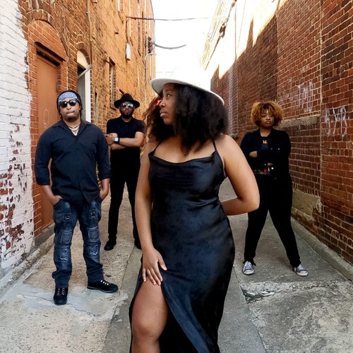 four members of the phoebes band standing in an alley with lead singer up front.